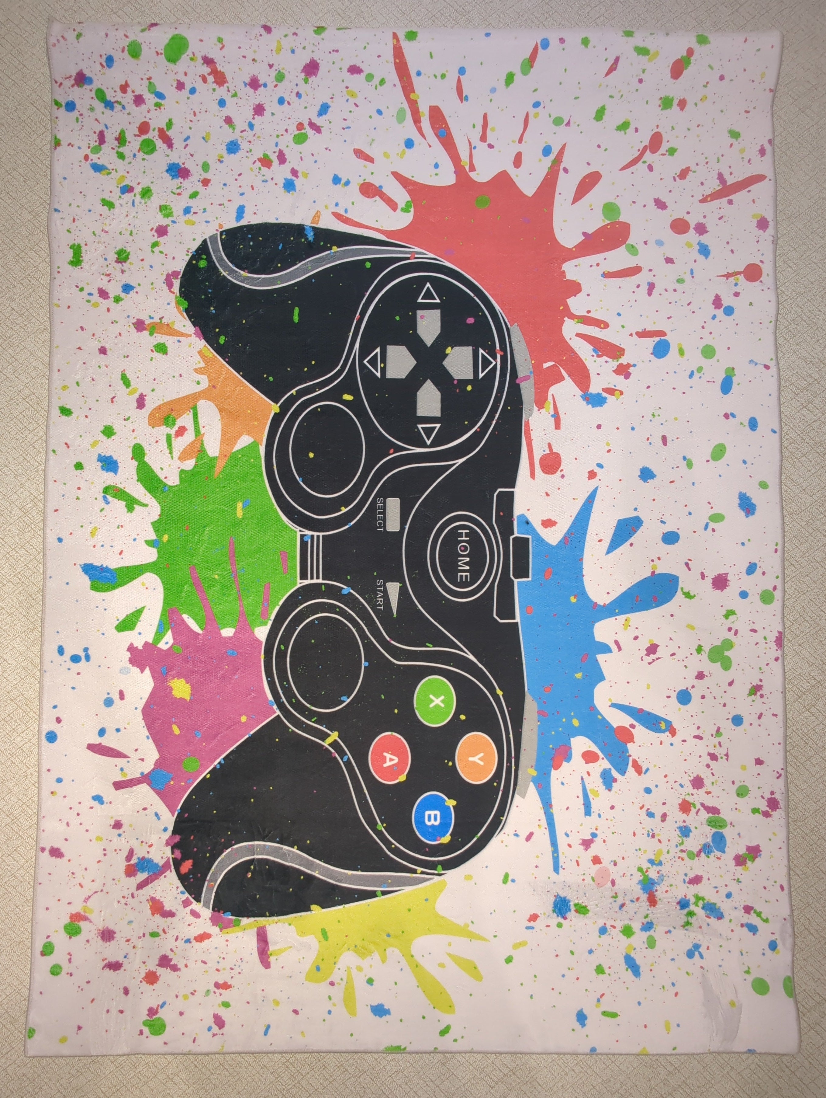 Colorful splatter design with a black gaming controller on a white background